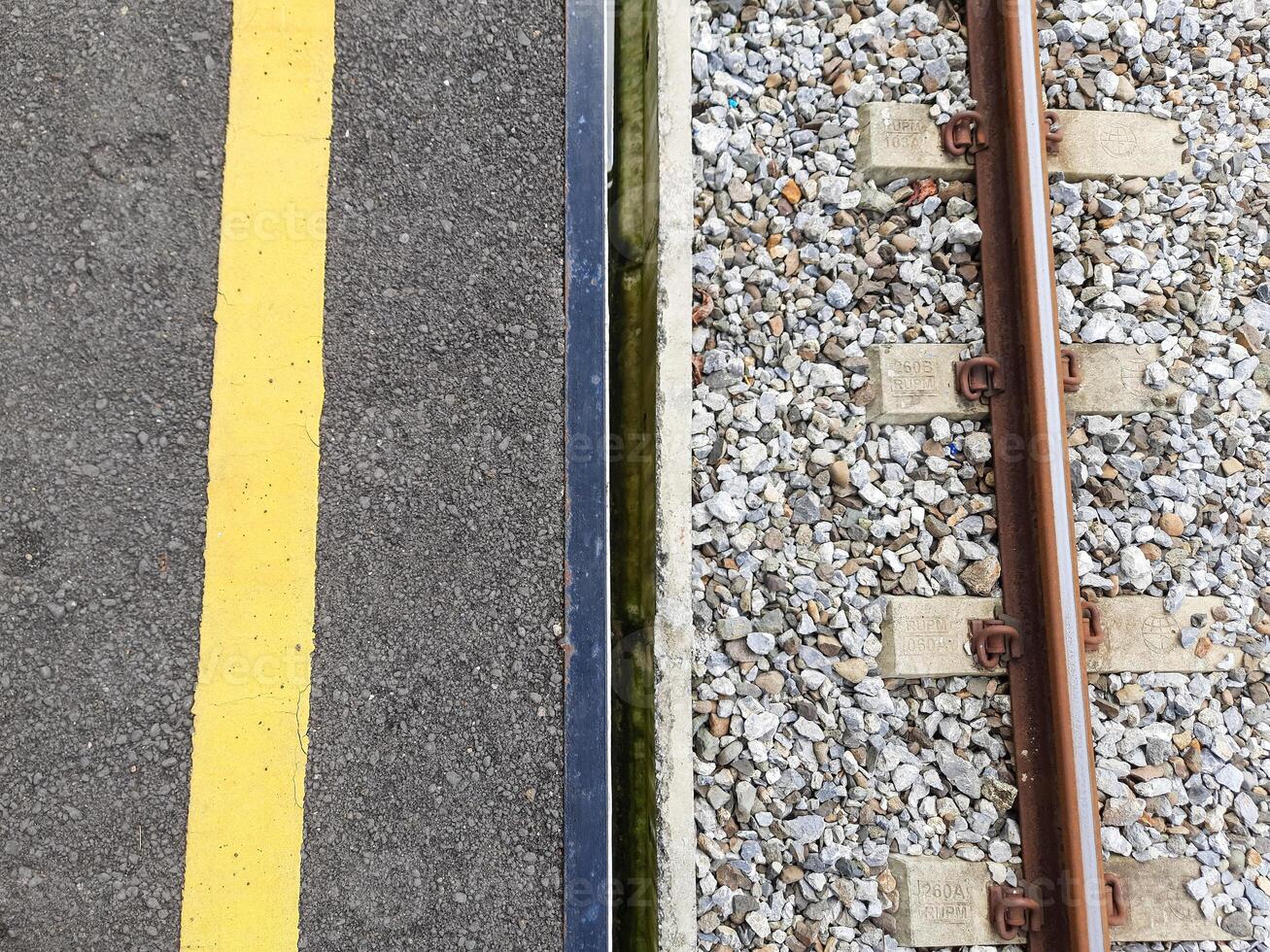 half asphalt and half railroad tracks. top view of indonesian railway station platform photo