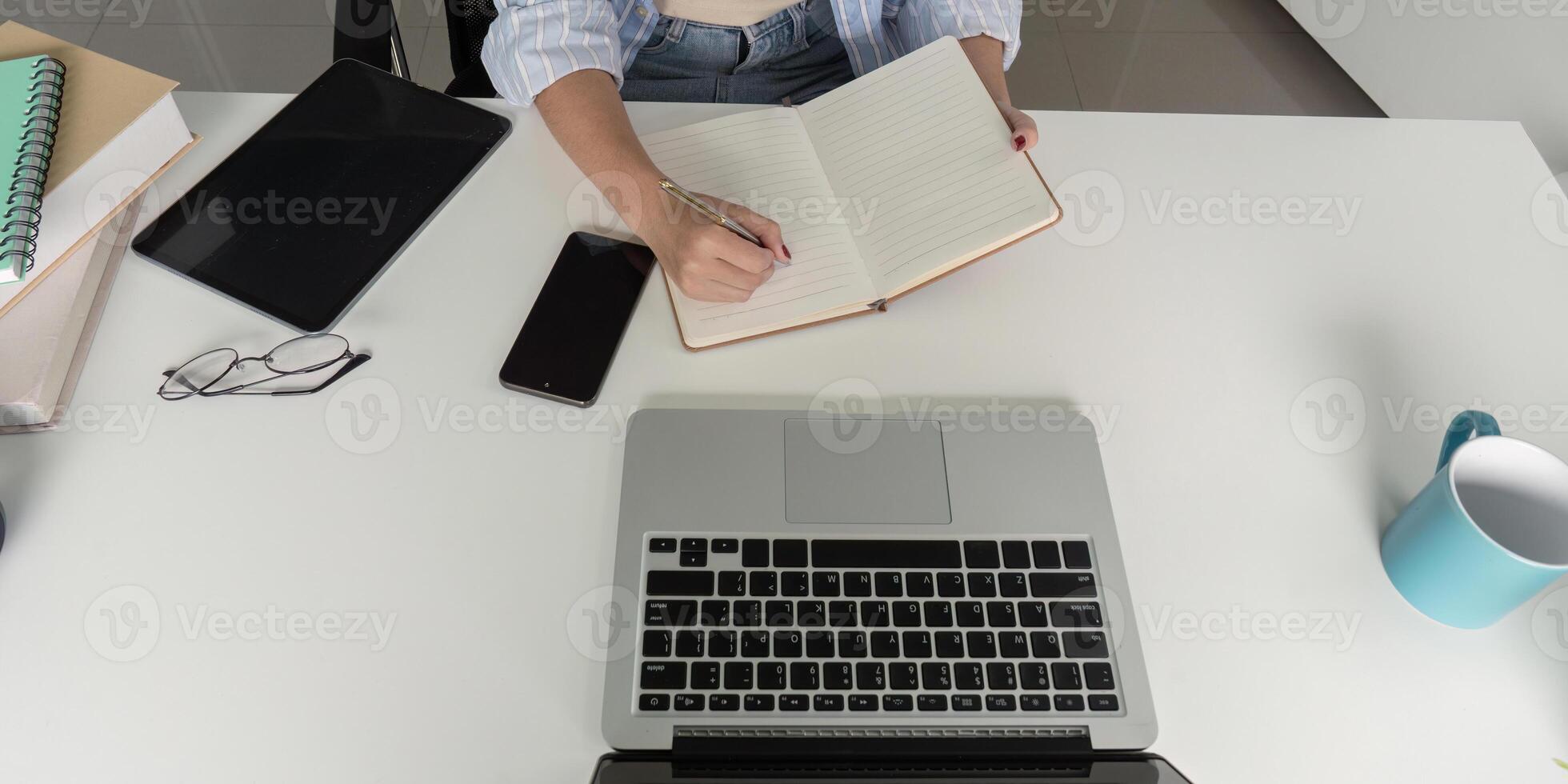 Hands of a Student Taking Notes While Studying Online photo