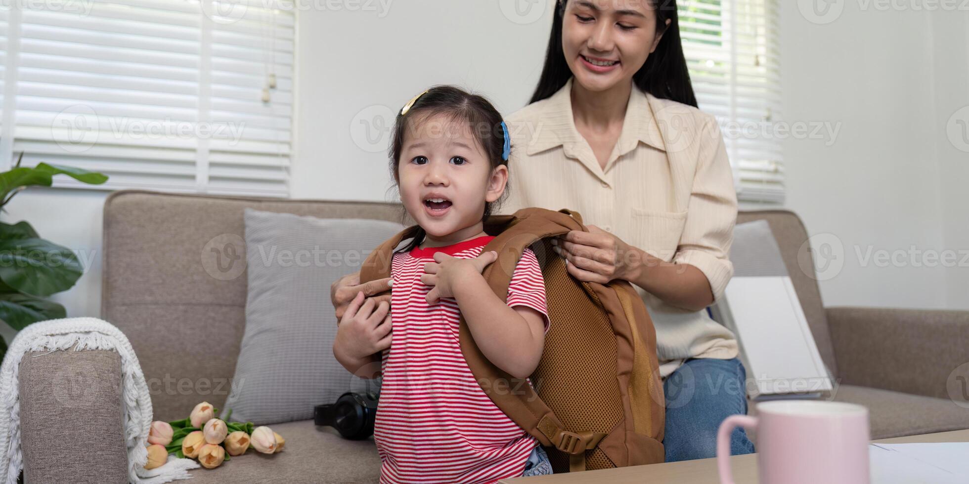 Mother Fitting Backpack on Excited Daughter for School Day photo