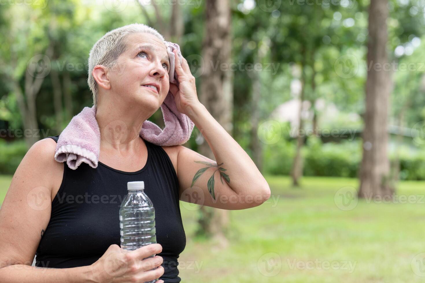 Elderly Woman Focusing on Hydration and Health in a Tranquil Natural Setting photo
