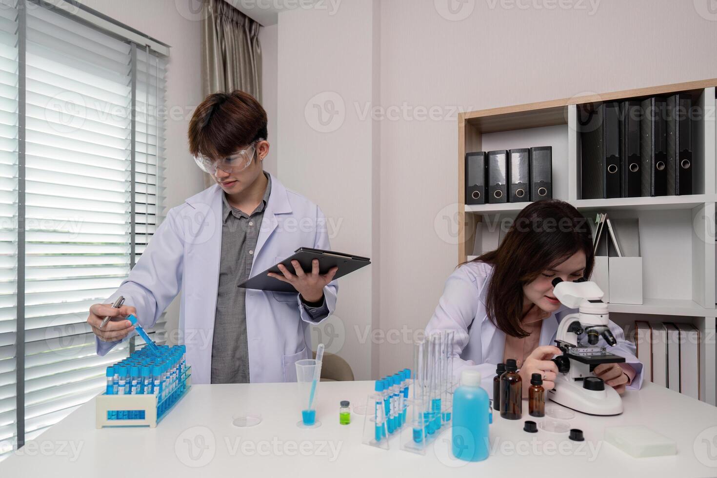Researcher Performing Dual Experimentation. Microscope Analysis and Digital Data Entry photo