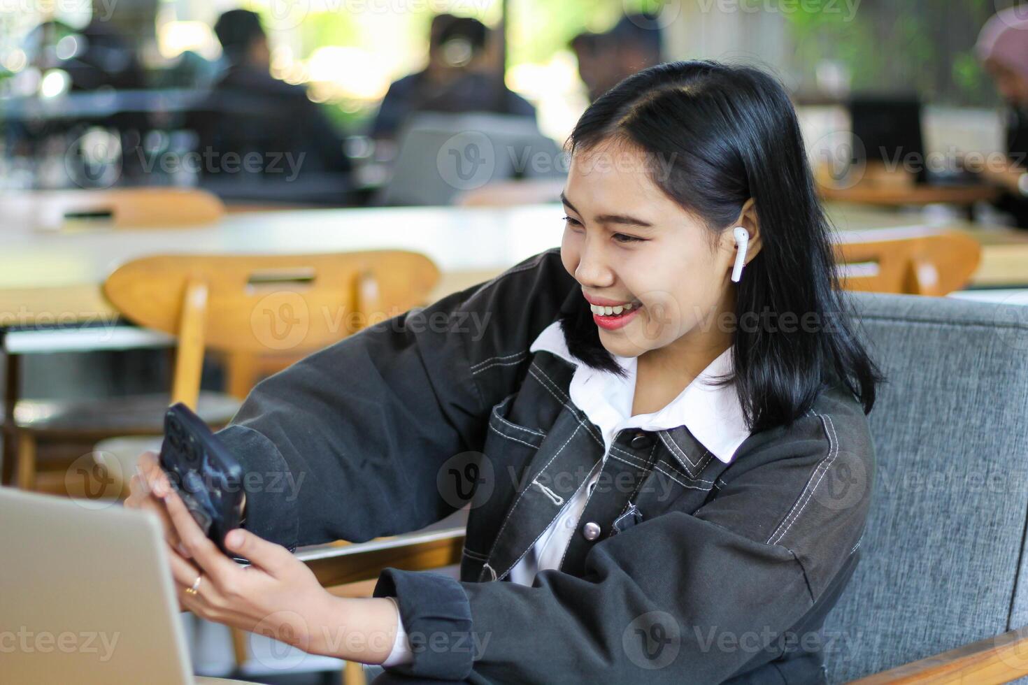excited asian woman taking selfie in cafe with her smartphone hold on hand for social media photo