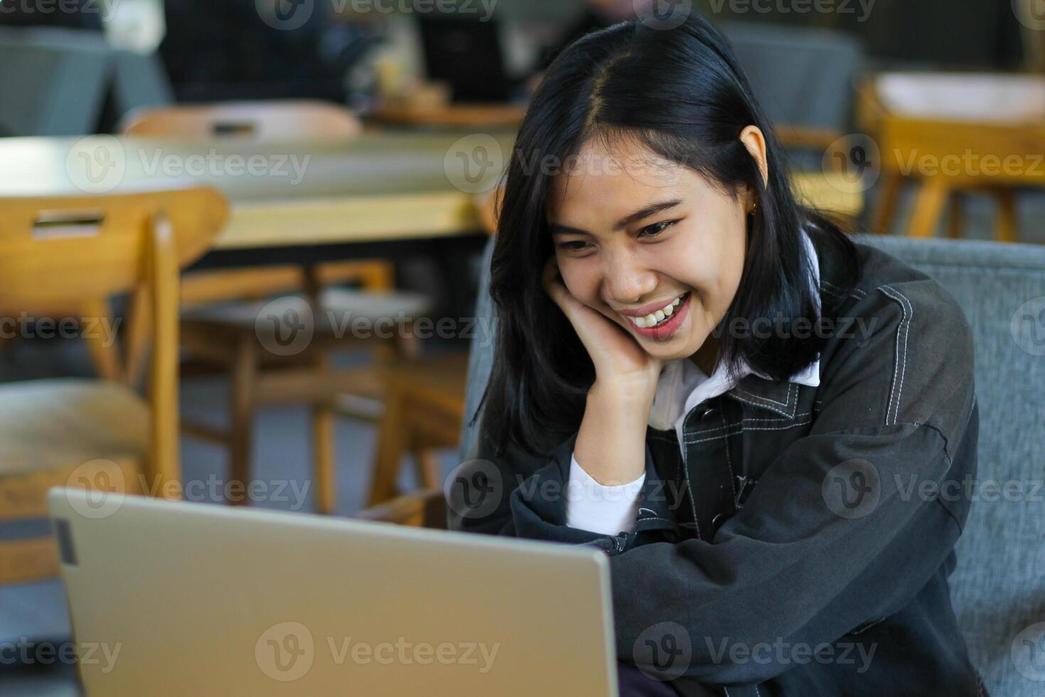 carefree asian woman using laptop in cafe doing virtual online meeting with client, browing social media and reading news photo