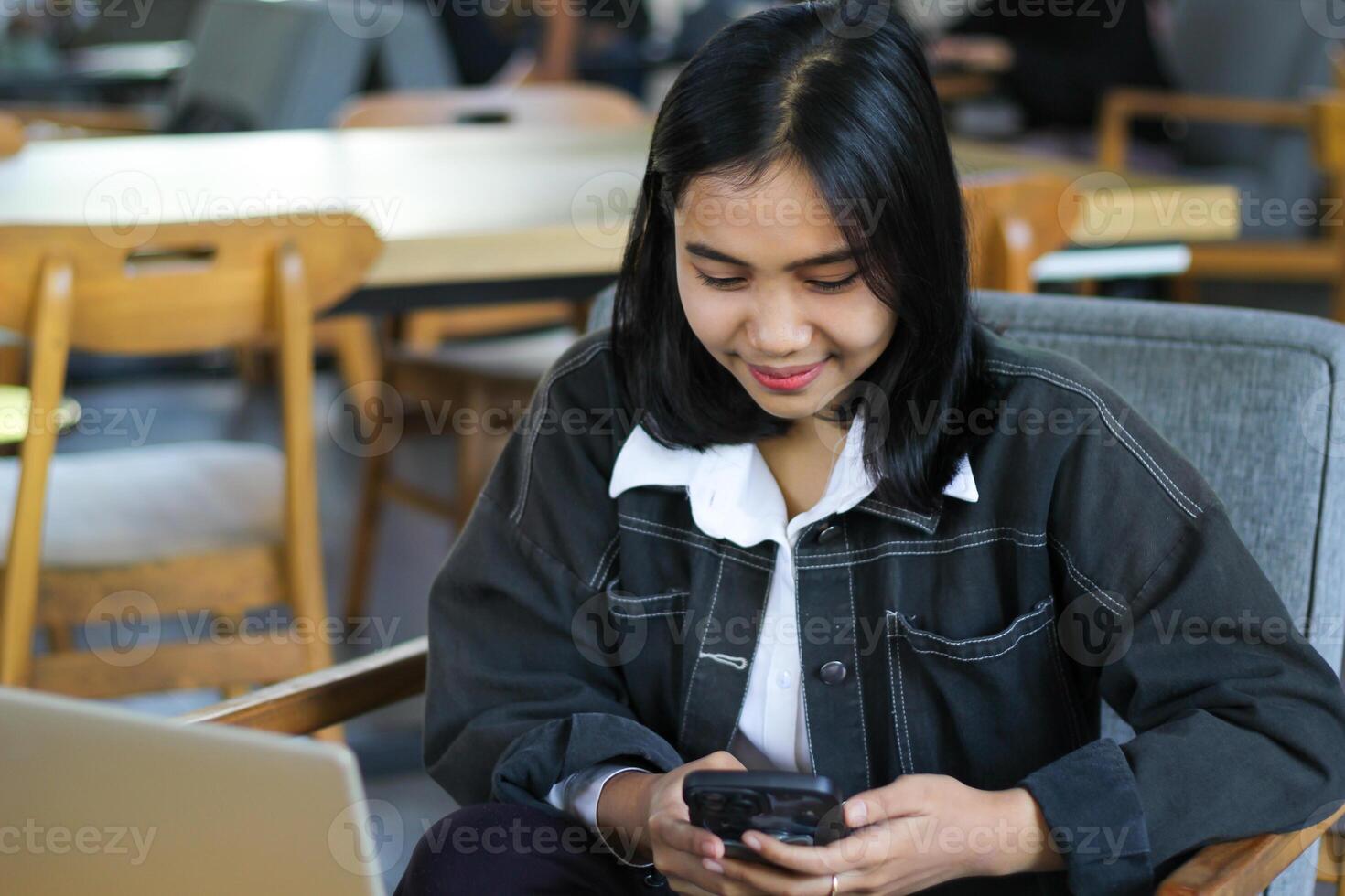 smiling asian woman sitting in cafe using smartphone to surfing in cyberspace and reading news, female doing online shopping photo