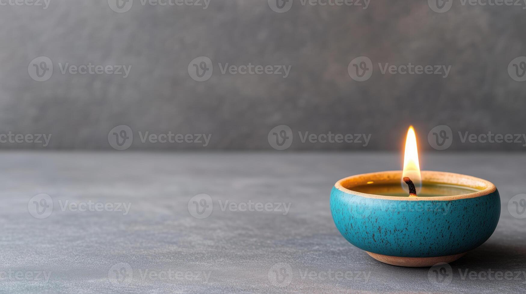 Small blue candle or oil lamp providing a warm light against a gray background with copy space photo