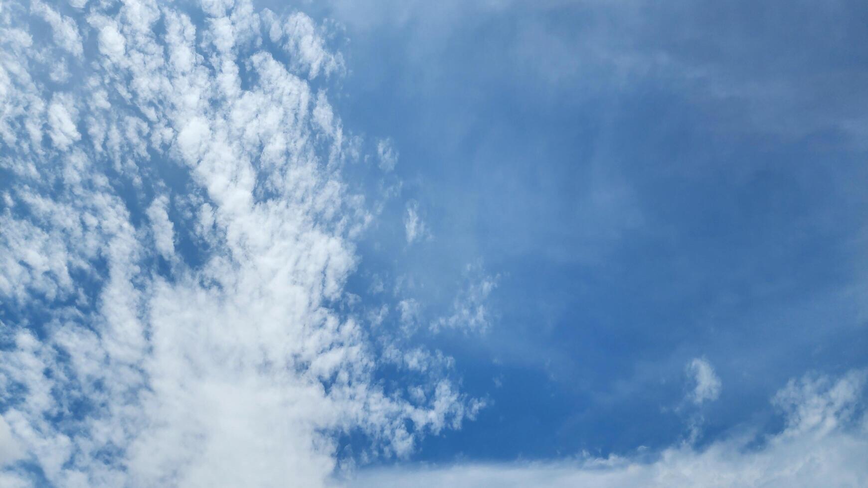 a blue sky with clouds and a plane flying in it photo