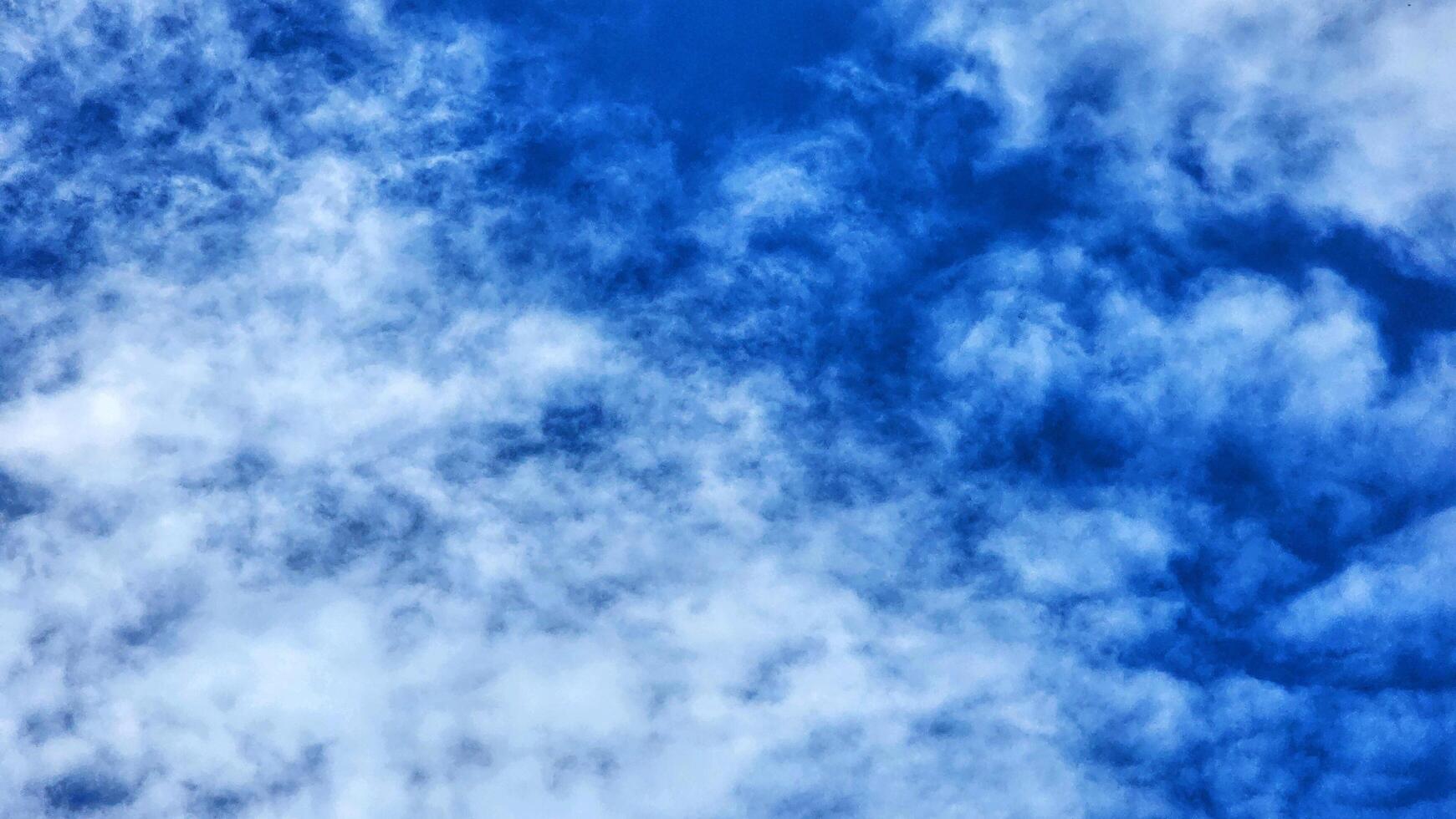 a blue sky with clouds and a plane flying in it photo