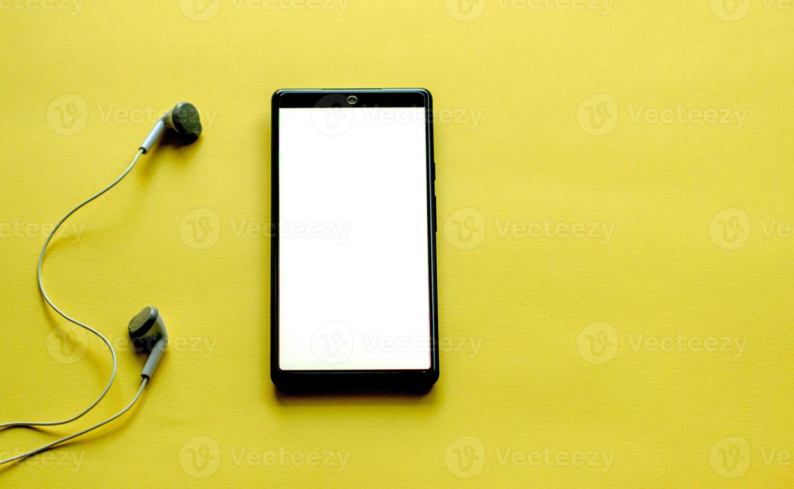 a cell phone on a yellow background with old style headphones photo