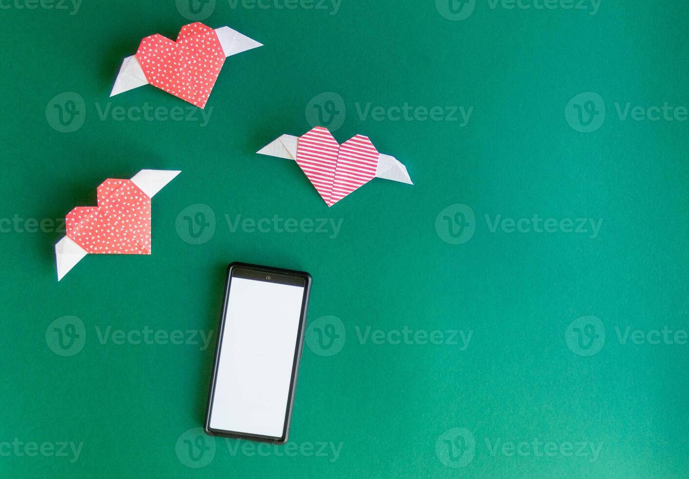 paper red hearts circle around the phone. abstraction on the theme of messages and communication photo