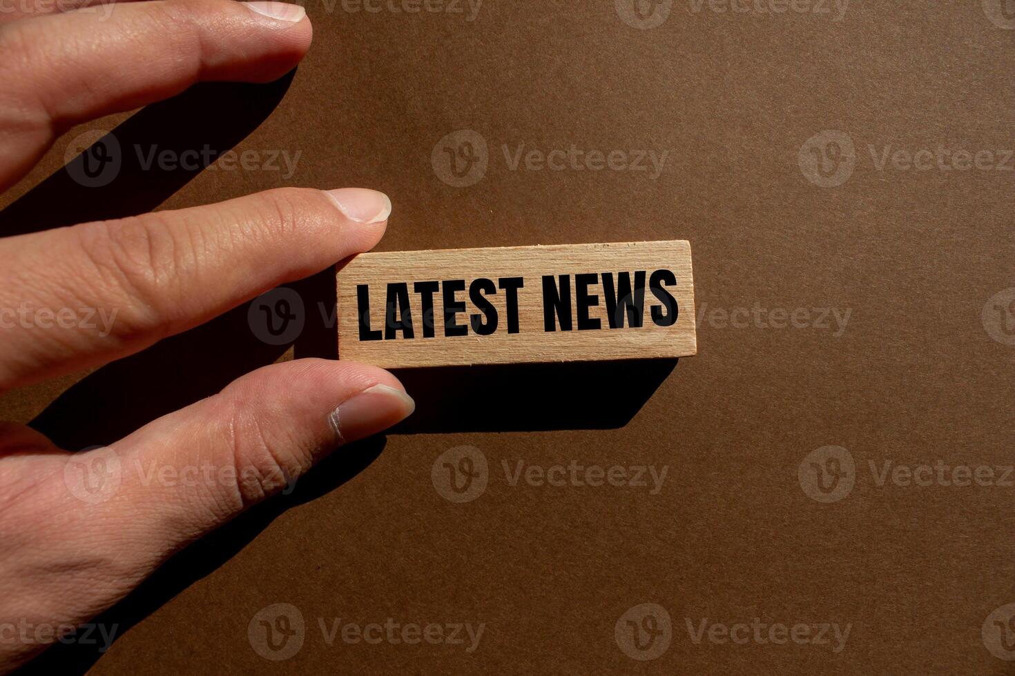 Latest news message written on wooden block with brown background. Conceptual latest news symbol. Copy space. photo