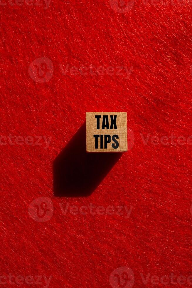 Tax tips message written on wooden cube with red background. Conceptual tax tips symbol. Copy space. photo