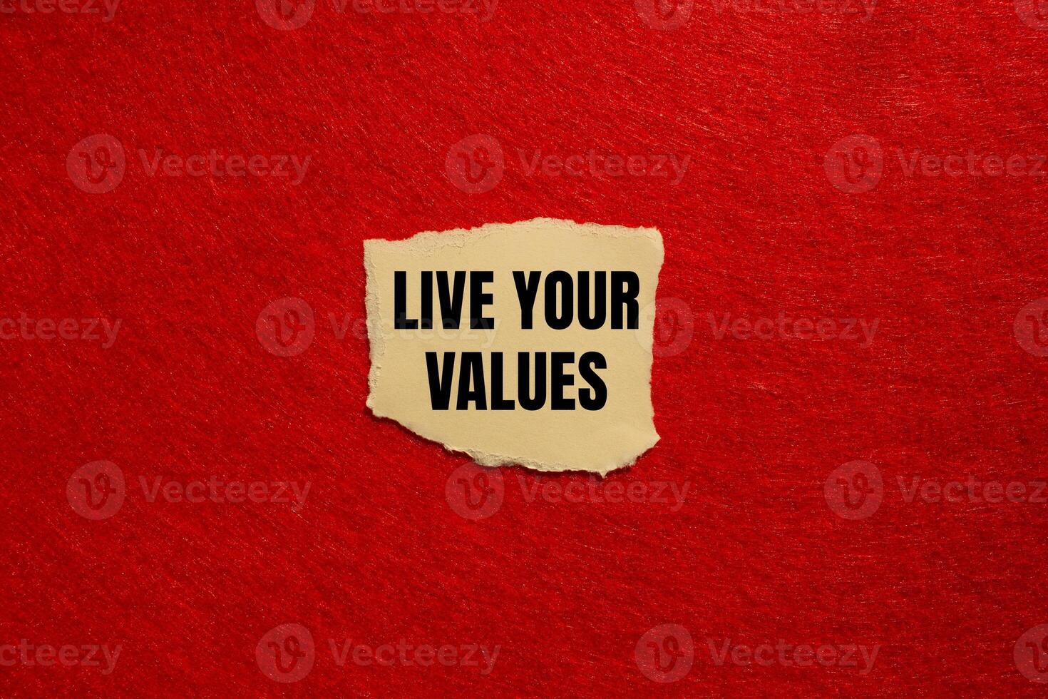 Live your values message written on ripped torn paper piece with red background. Conceptual live your values symbol. Copy space. photo
