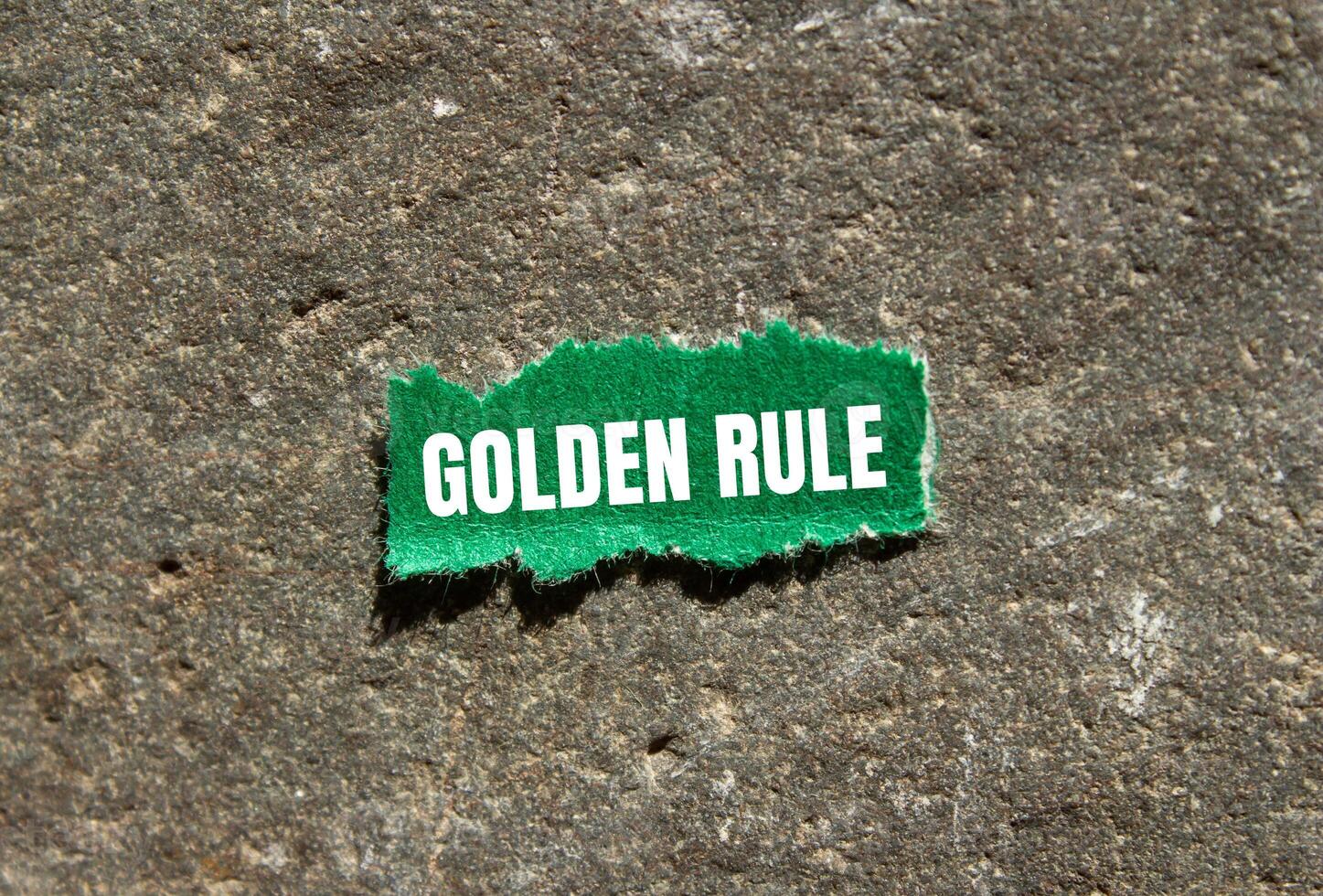 Golden rule message written on ripped green torn paper piece with stone background. Conceptual golden rule symbol. Copy space. photo