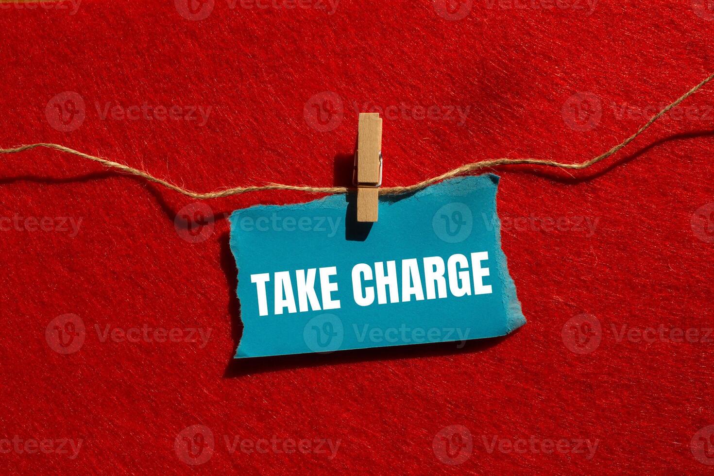 Take charge message written on ripped torn blue paper piece with red background. Conceptual take charge symbol. Copy space. photo