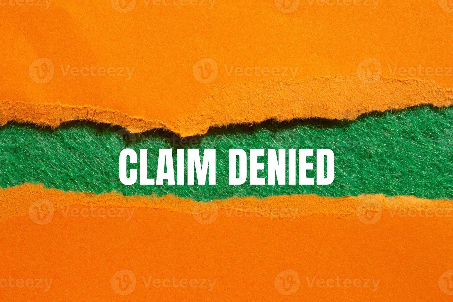 Claim denied message written on ripped torn orange paper with green background. Conceptual claim denied symbol. Copy space. photo