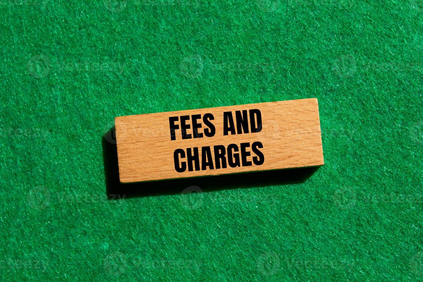 Fees and charges message written on wooden block with green background. Conceptual fees and charges symbol. Copy space. photo