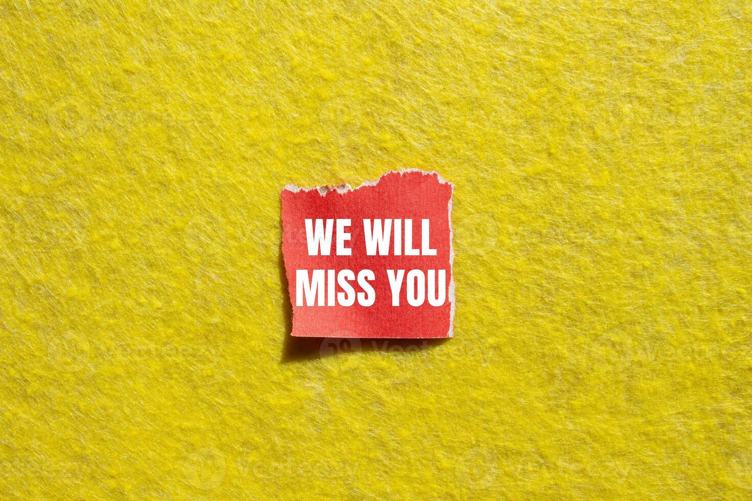 We will miss you message written on ripped torn red paper piece with yellow background. Conceptual we will miss you symbol. Copy space. photo