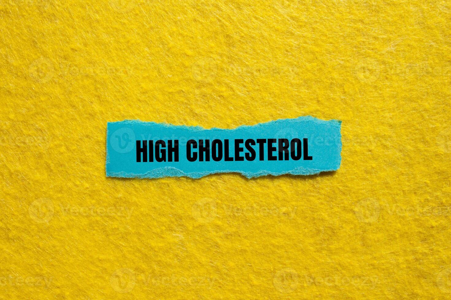 High cholesterol message written on ripped torn blue paper piece with yellow background. Conceptual high cholesterol symbol. Copy space. photo