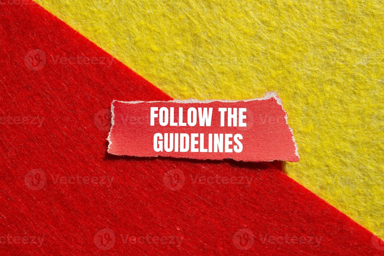 Follow the guidelines message written on ripped torn red paper piece with yellow red background. Conceptual follow the guidelines symbol. Copy space. photo