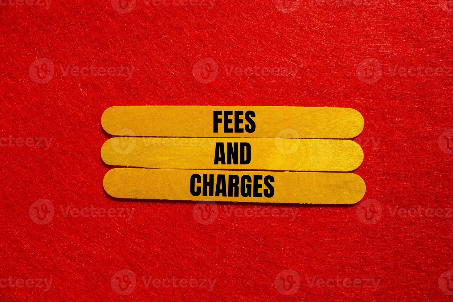 Fees and charges message written on yellow wooden sticks with red background. Conceptual fees and charges symbol. Copy space. photo