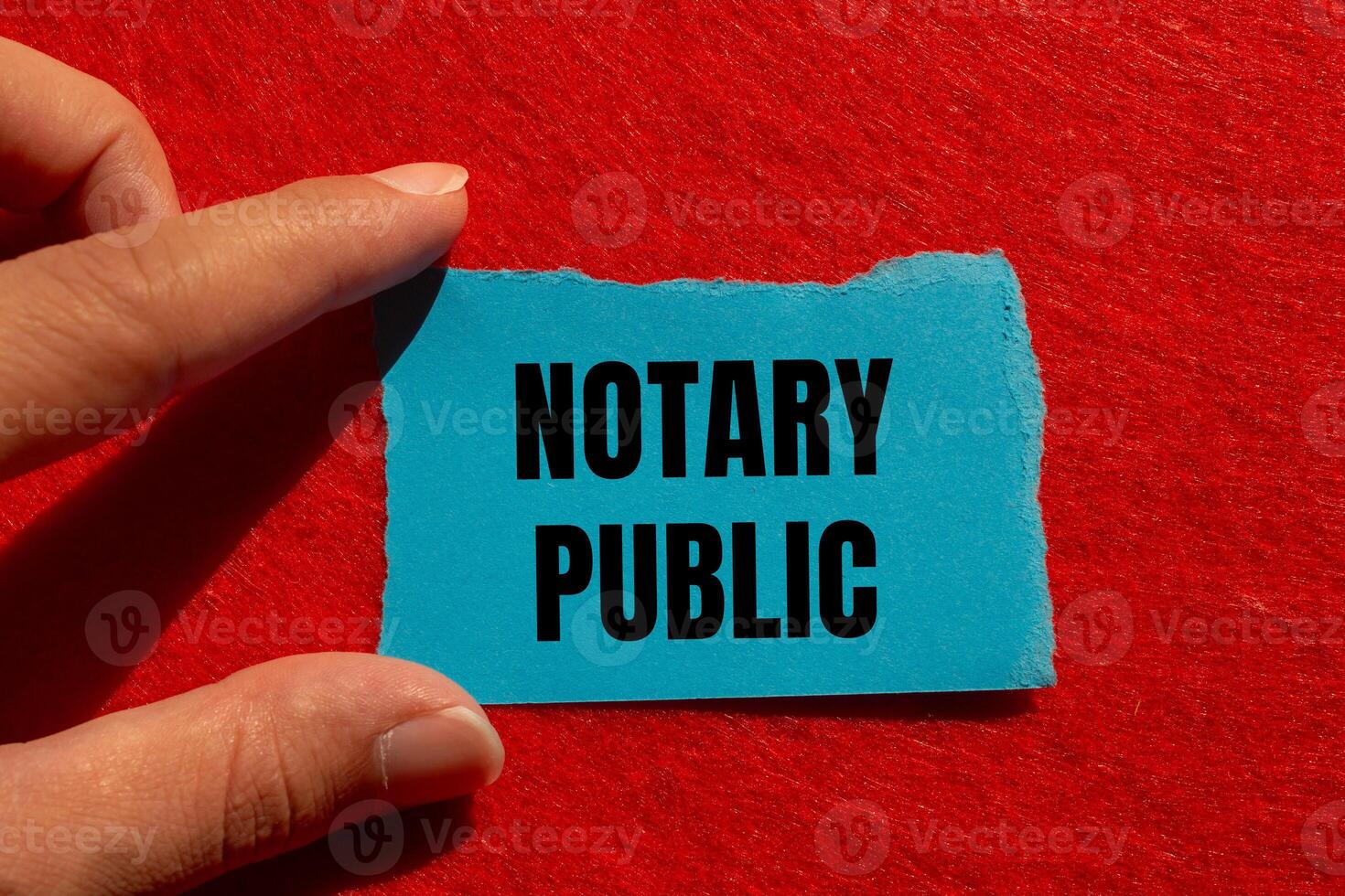 Notary public message written on ripped torn blue paper piece with red background. Conceptual notary public symbol. Copy space. photo