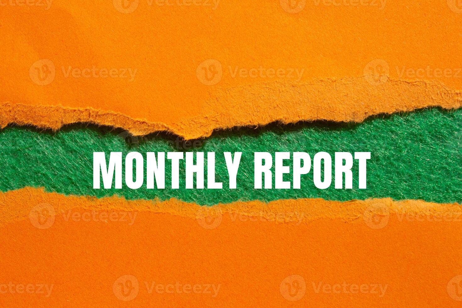 Monthly report message written on ripped torn orange paper with green background. Conceptual monthly report symbol. Copy space. photo