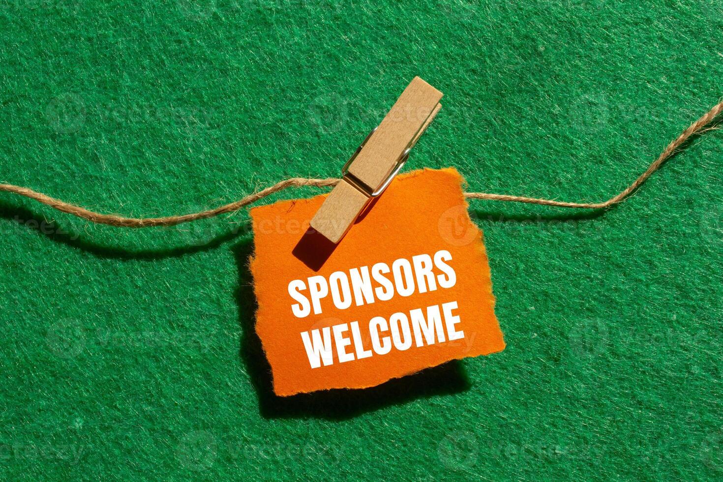 Sponsors welcome message written on ripped torn orange paper piece with green background. Conceptual sponsors welcome symbol. Copy space. photo