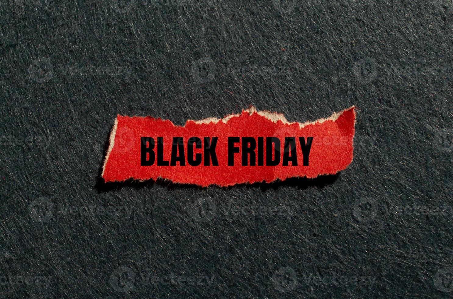 Black friday message written on ripped red torn paper piece with gray background. Conceptual black friday symbol. Copy space. photo