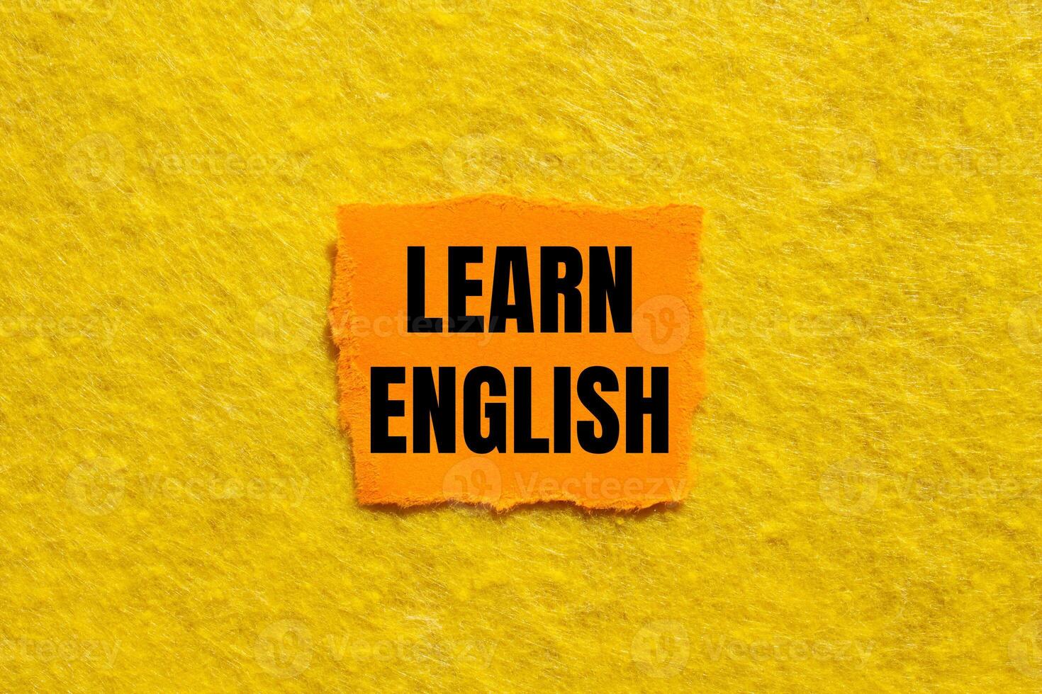 Learn english message written on ripped torn orange paper piece with yellow background. Conceptual learn english symbol. Copy space. photo