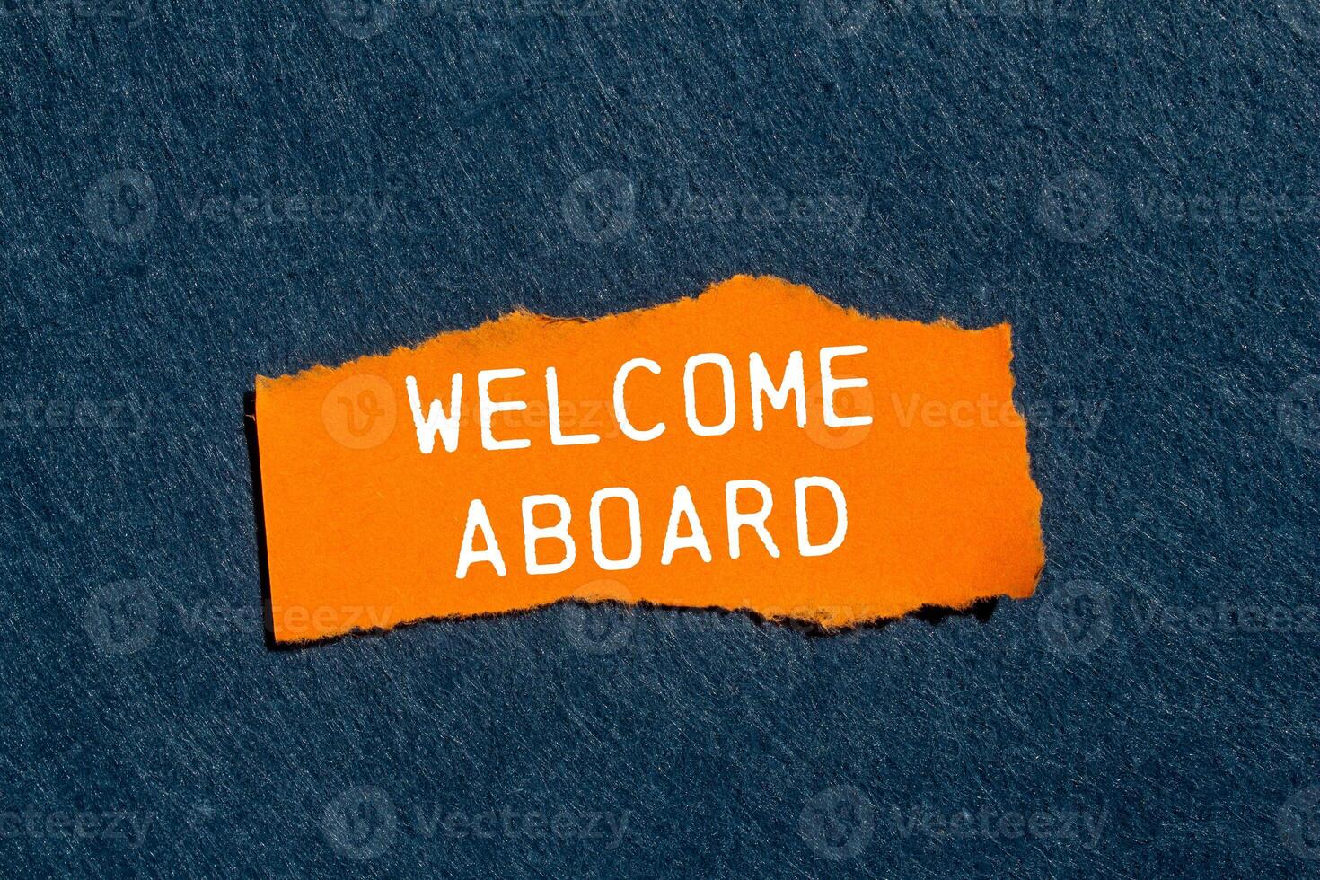 Welcome aboard message written on ripped torn orange paper piece with gray felt background. Conceptual welcome aboard symbol. Copy space. photo