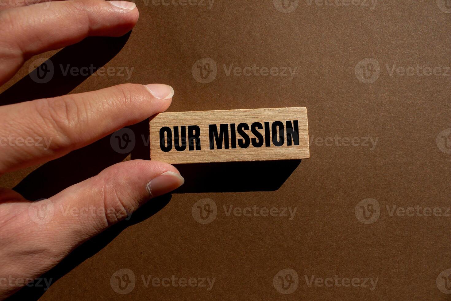 Our mission message written on wooden block with brown background. Conceptual our mission symbol. Copy space. photo