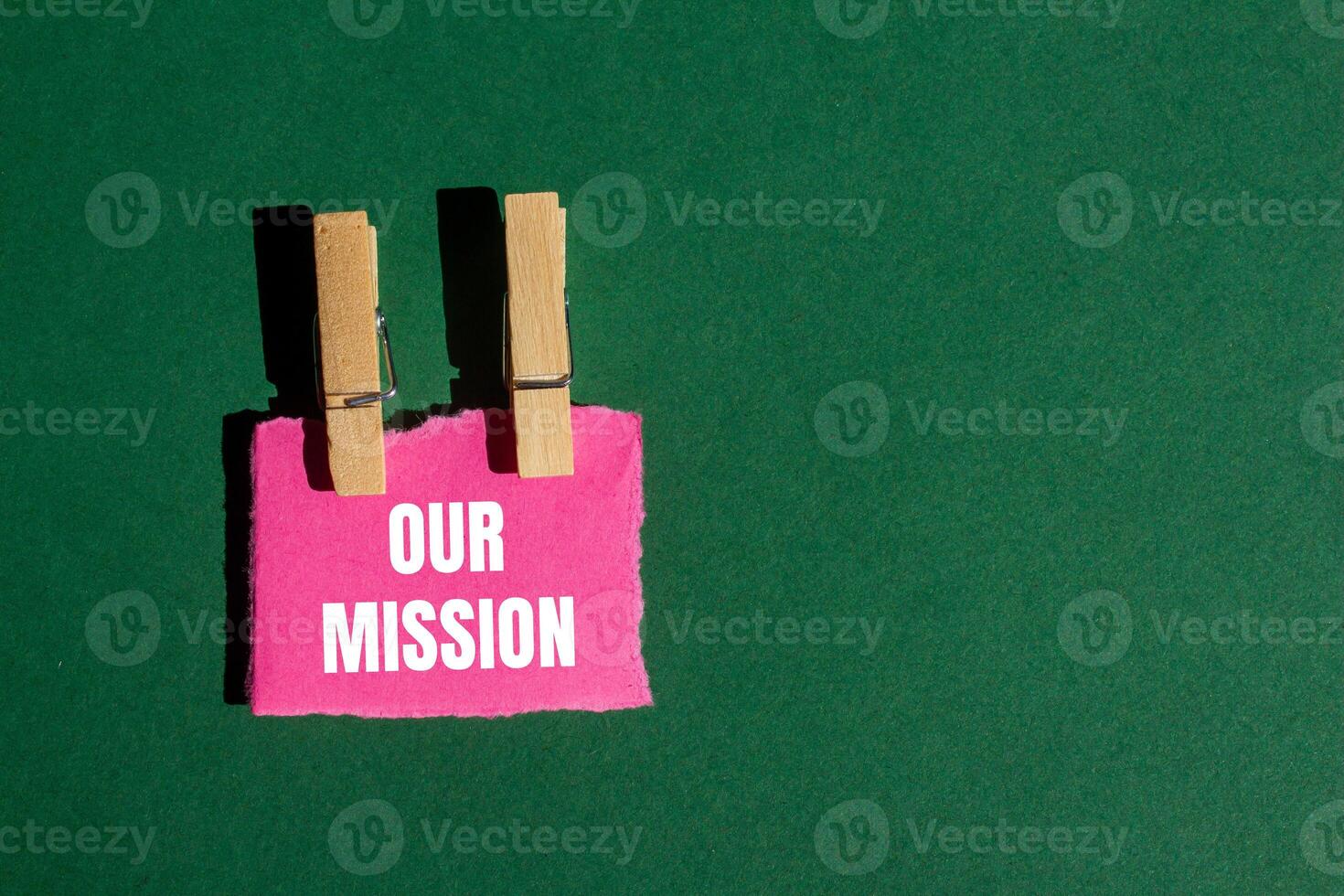 Our mission message written on ripped torn pink paper piece with green background. Conceptual our mission symbol. Copy space. photo