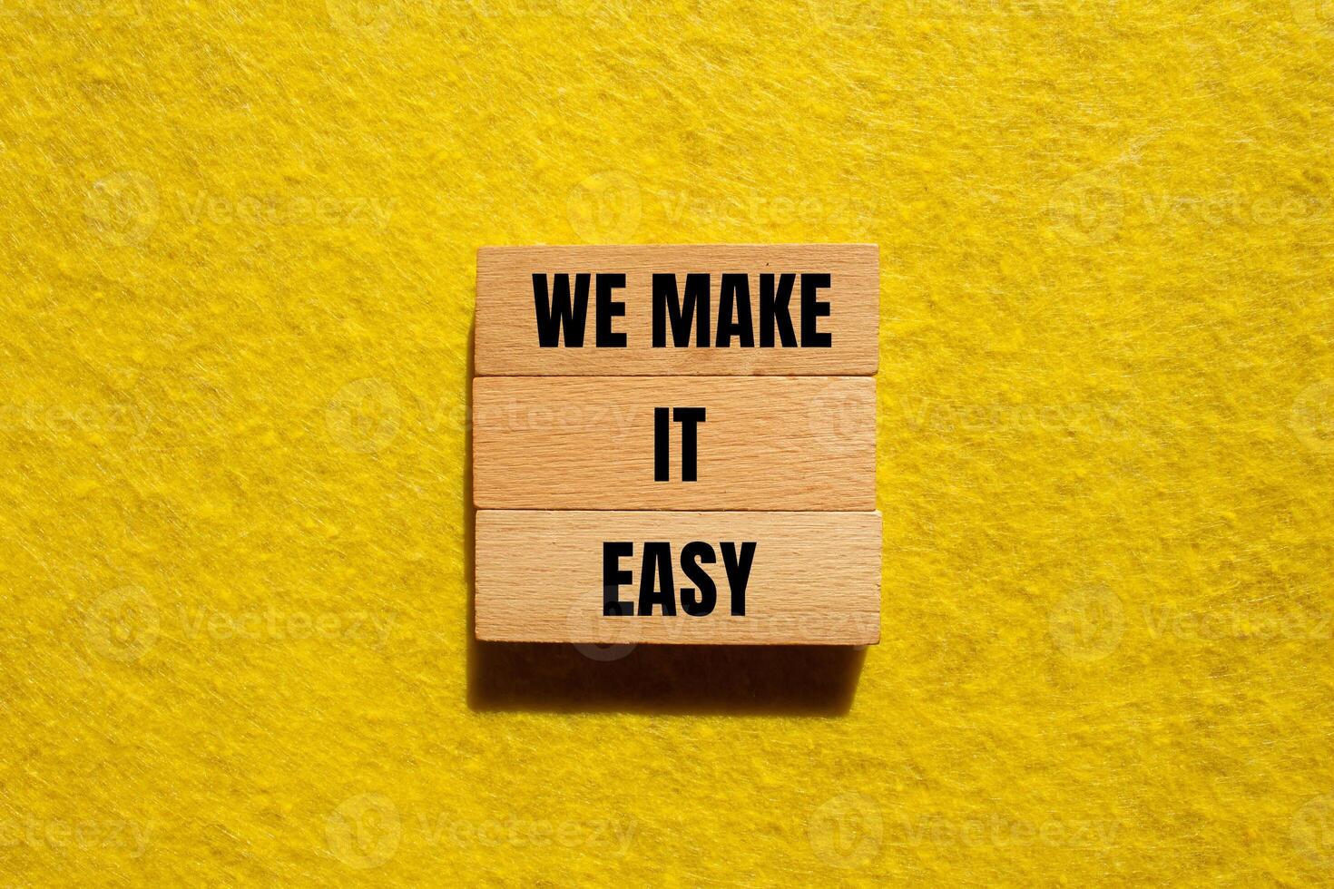 We make it easy message written on wooden blocks with yellow background. Conceptual we make it easy symbol. Copy space. photo