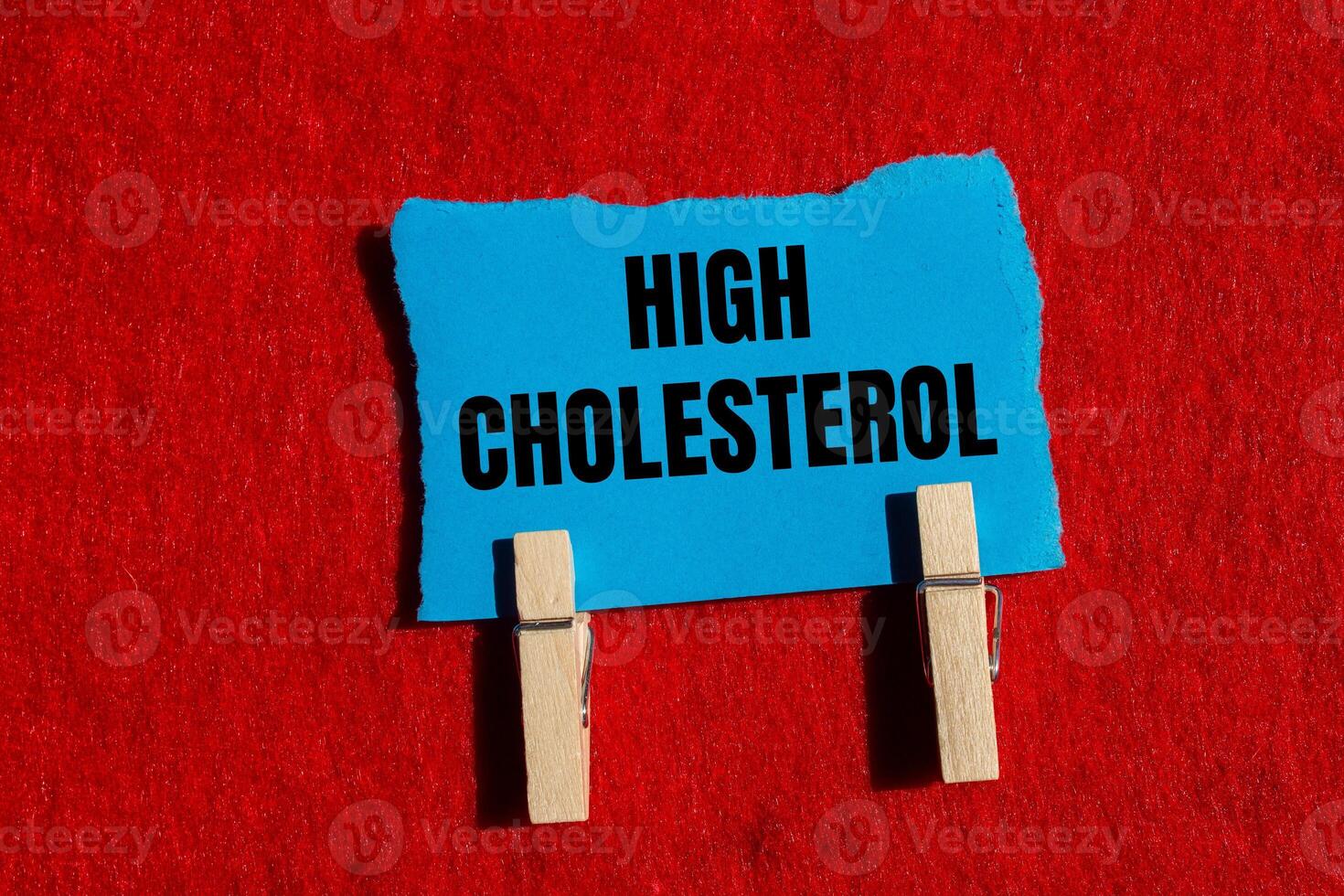 High cholesterol message written on ripped torn blue paper piece with red background. Conceptual high cholesterol symbol. Copy space. photo