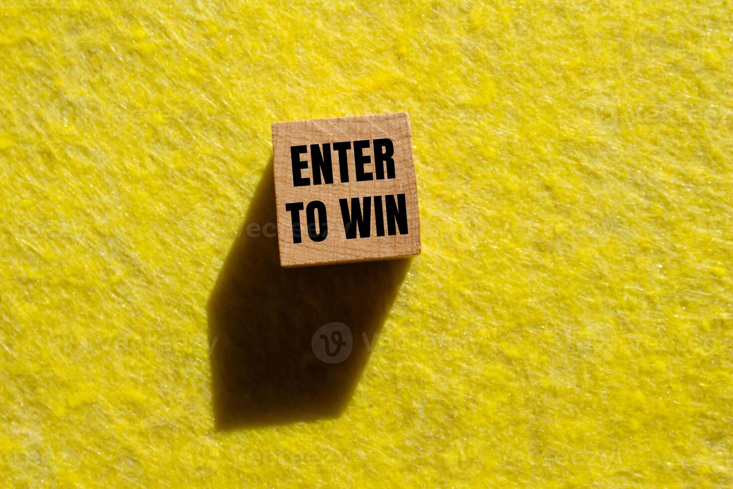 Enter to win message written on wooden cube with yellow background. Conceptual enter to win symbol. Copy space. photo