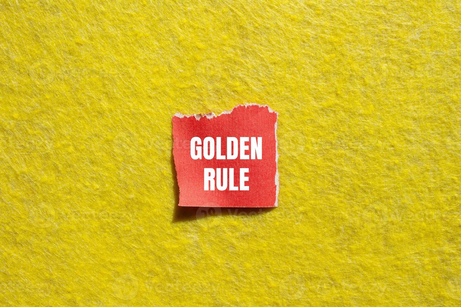 Golden rule message written on ripped torn red paper piece with yellow background. Conceptual golden rule symbol. Copy space. photo