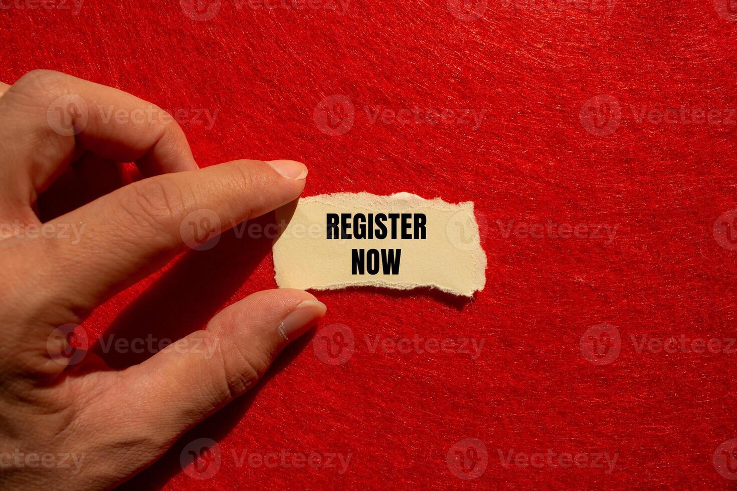 Register now message written on ripped torn paper piece with red background. Conceptual register now symbol. Copy space. photo
