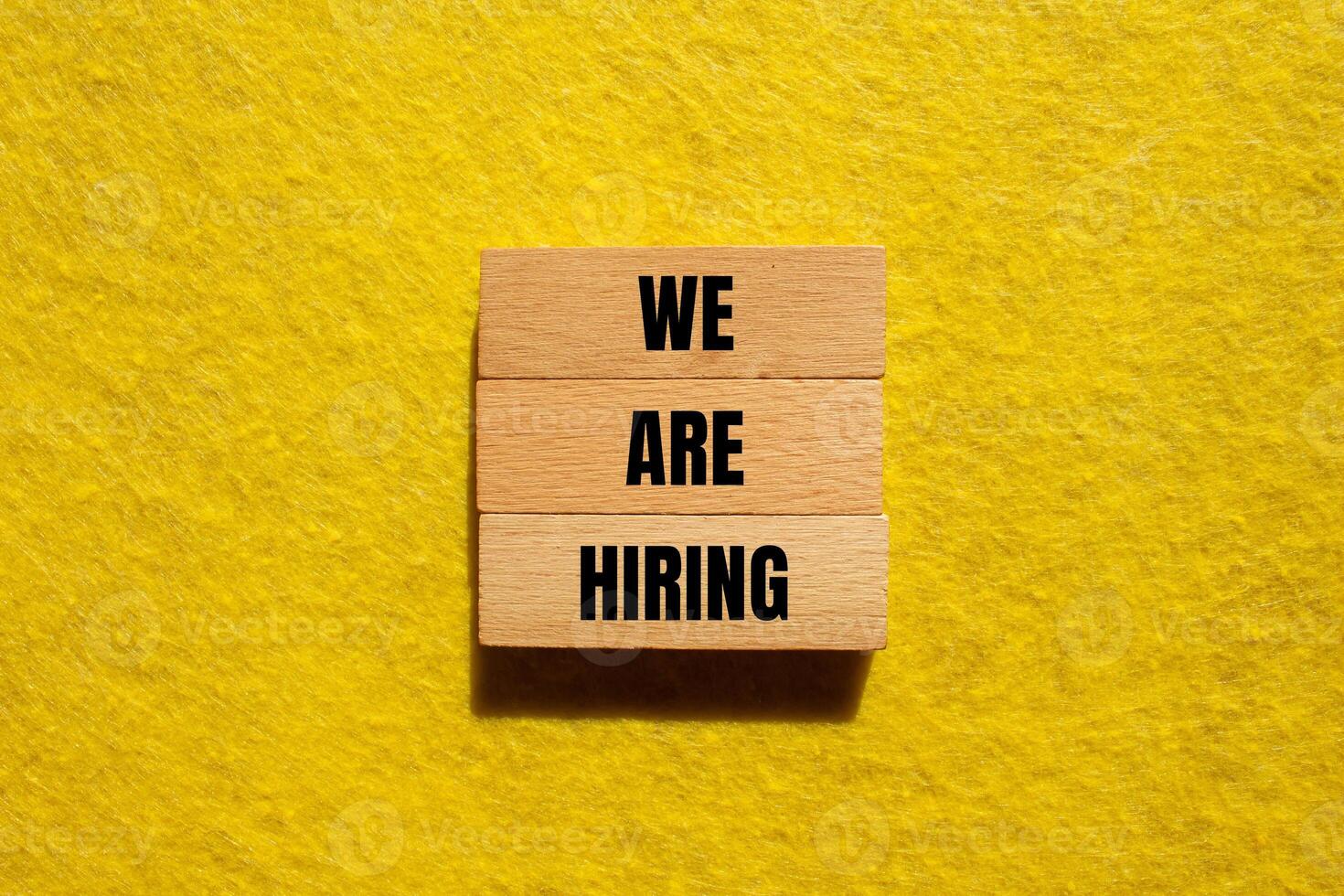We are hiring message written on wooden blocks with yellow background. Conceptual we are hiring symbol. Copy space. photo