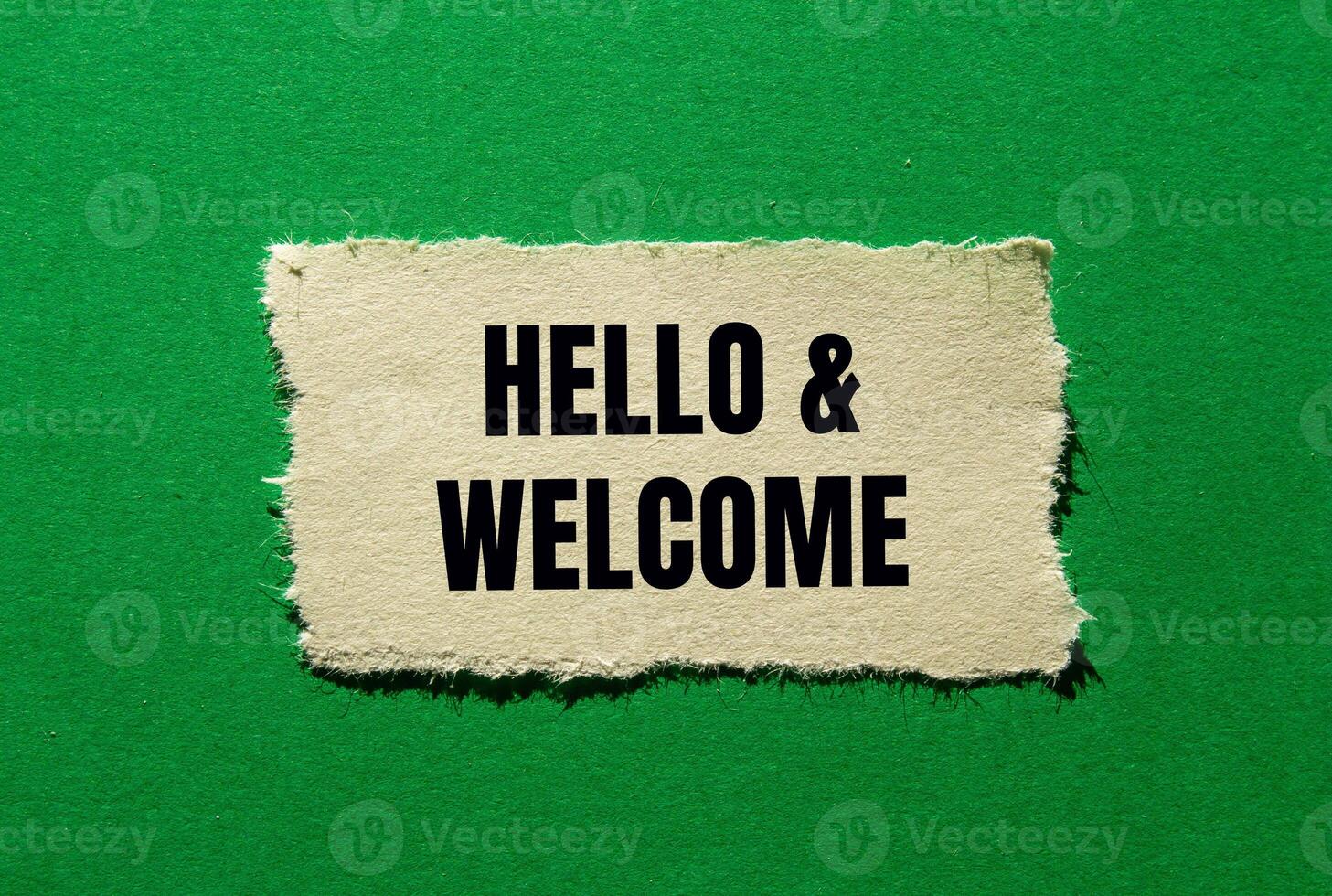 Hello and welcome message written on ripped torn paper piece on green background. Conceptual hello and welcome symbol. Copy space. photo