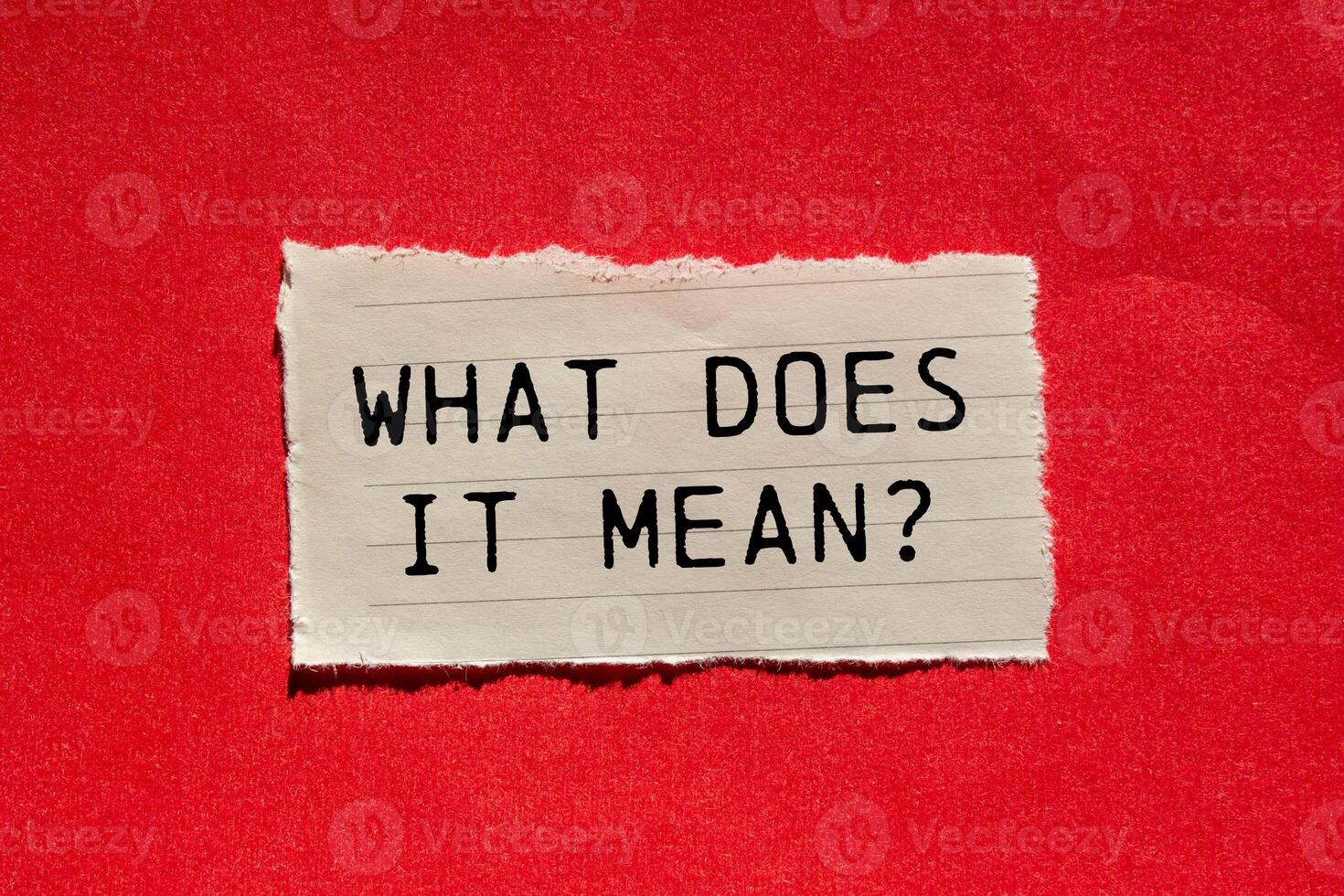 What does it mean question written on ripped torn paper piece on red background. Conceptual what does it mean question symbol. Copy space. photo