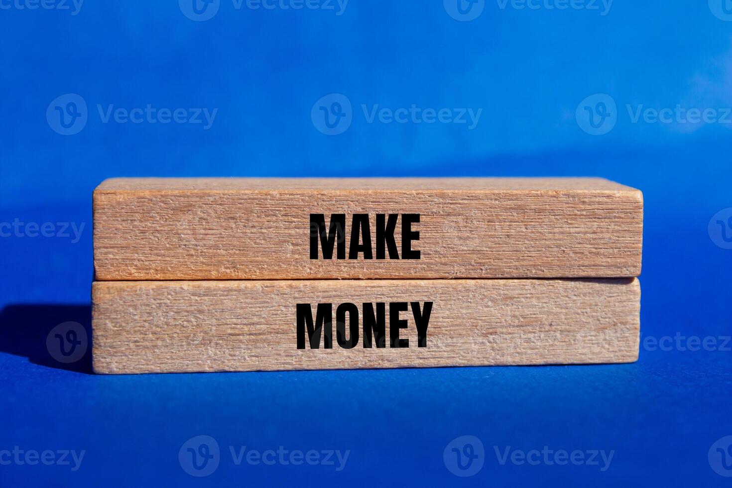 Make money message written on wooden blocks with blue background. Conceptual make money symbol. Copy space. photo