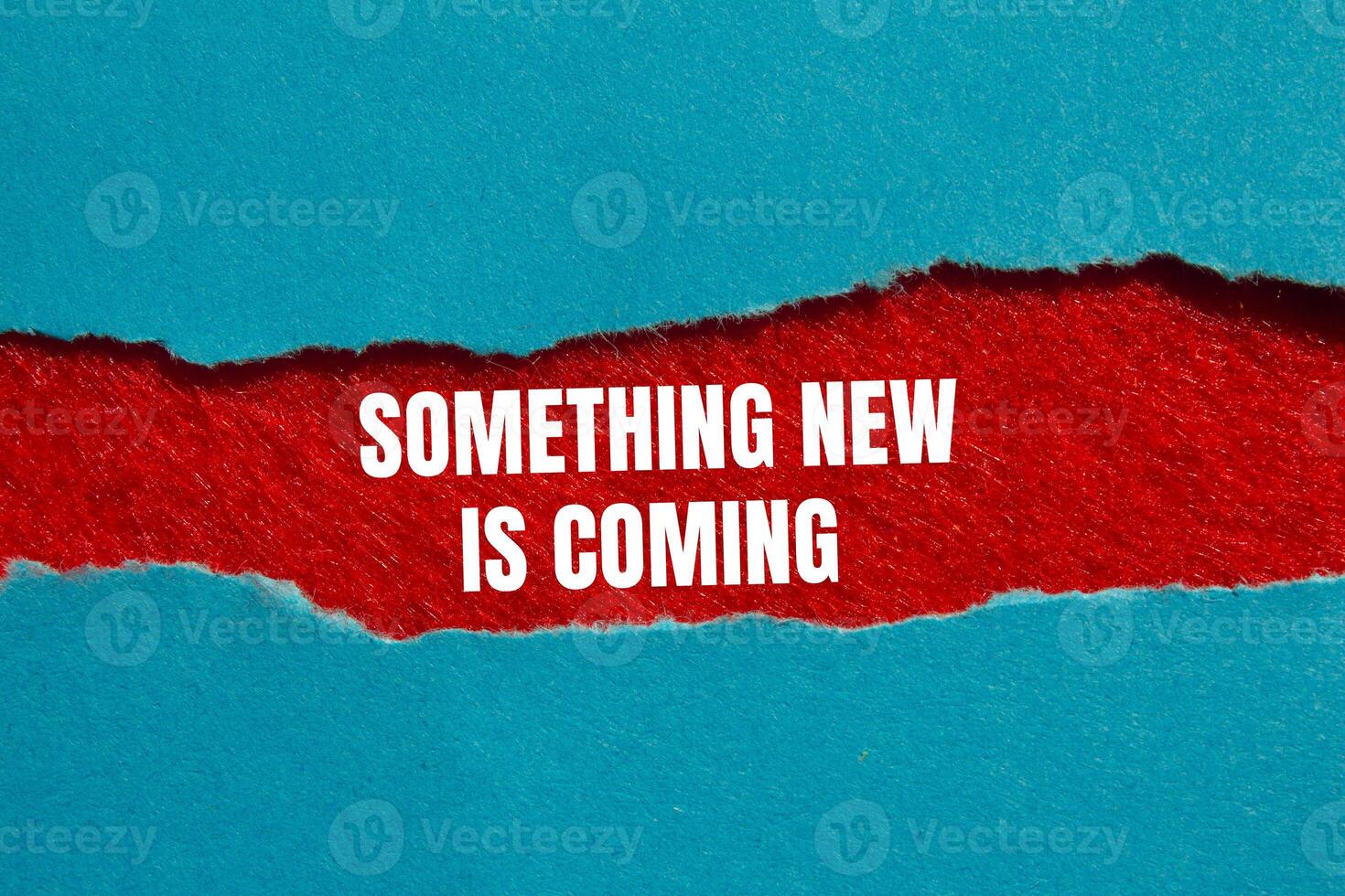 Something new is coming message written on ripped torn blue paper on red background. Conceptual something new is coming symbol. Copy space. photo