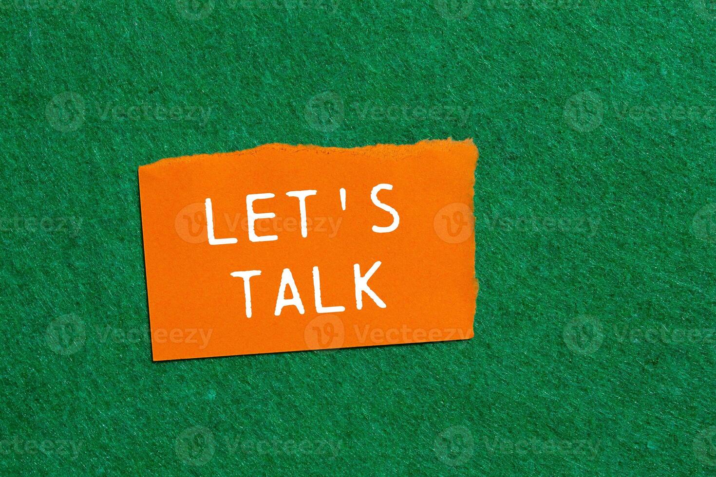 Let's talk message written on ripped orange torn paper piece on green background. Conceptual let's talk symbol. Copy space. photo