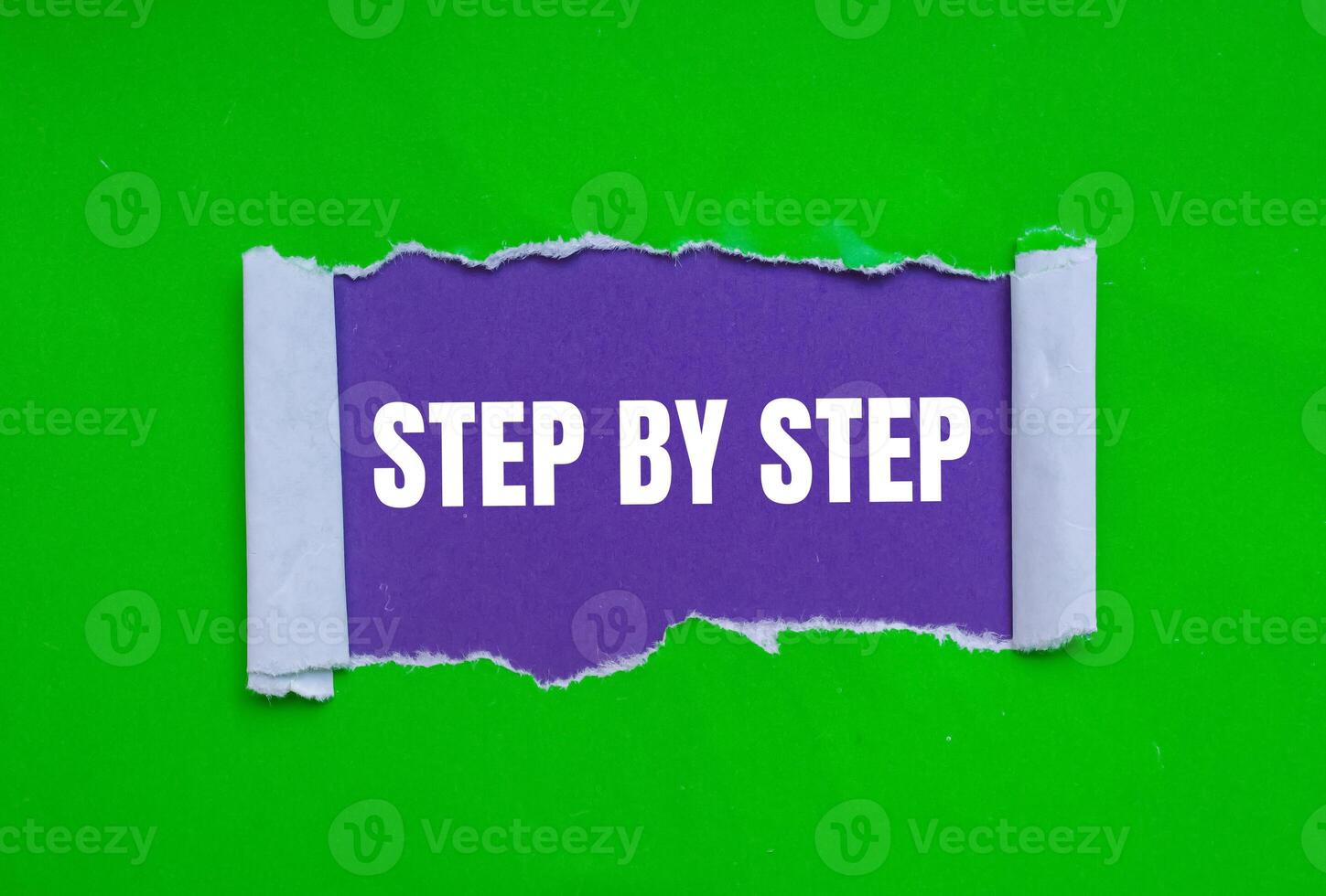 Step by step message written on ripped torn green paper on purple background. Conceptual step by step symbol. Copy space. photo