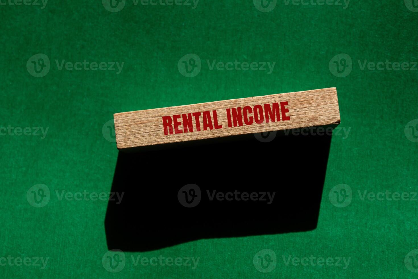 Rental income message written on wooden block with green background. Conceptual rental income symbol. Copy space. photo