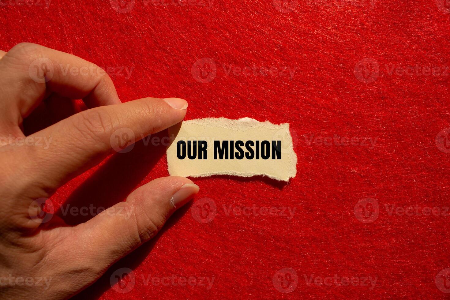 Our mission message written on ripped torn paper piece with red background. Conceptual our mission symbol. Copy space. photo