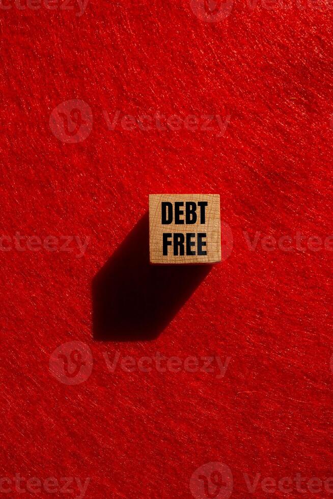 Debt free message written on wooden cube with red background. Conceptual debt free symbol. Copy space. photo