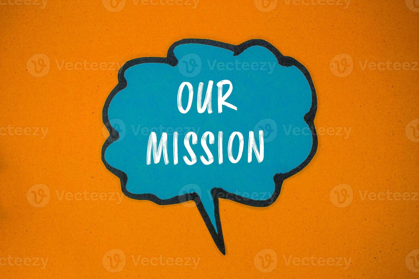 Our mission message written on blue paper speech bubble with orange background. Conceptual our mission symbol. Copy space. photo