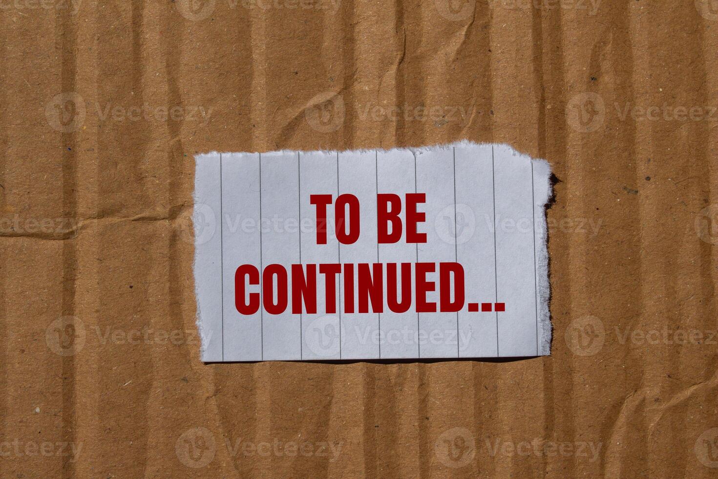 To be continued message written on ripped torn paper with cardboard background. Conceptual to be continued symbol. Copy space. photo