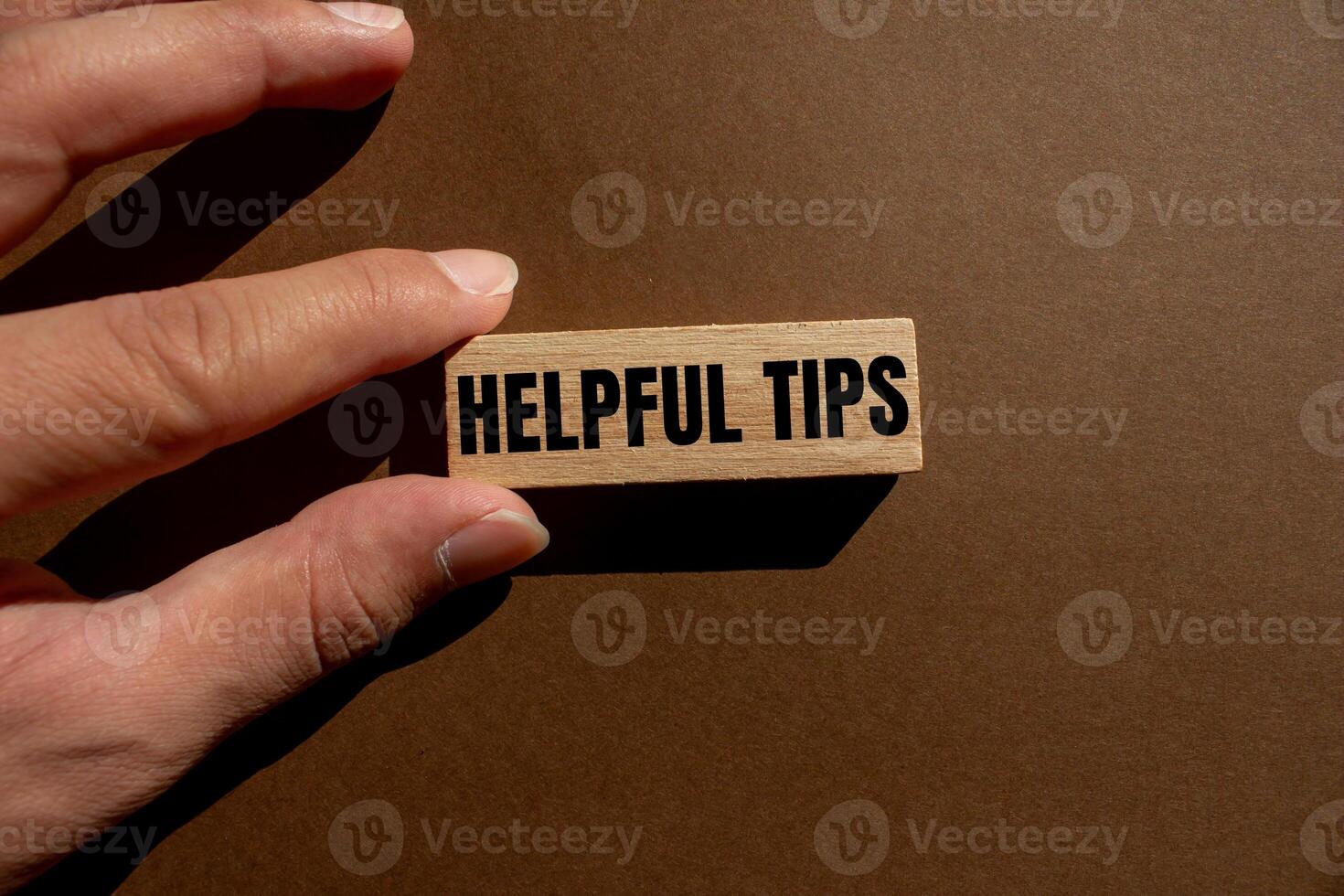 Helpful tips message written on wooden block with brown background. Conceptual helpful tips symbol. Copy space. photo